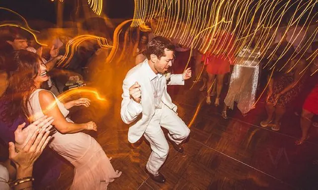 Groom dancing with guests on a packed wedding dance floor